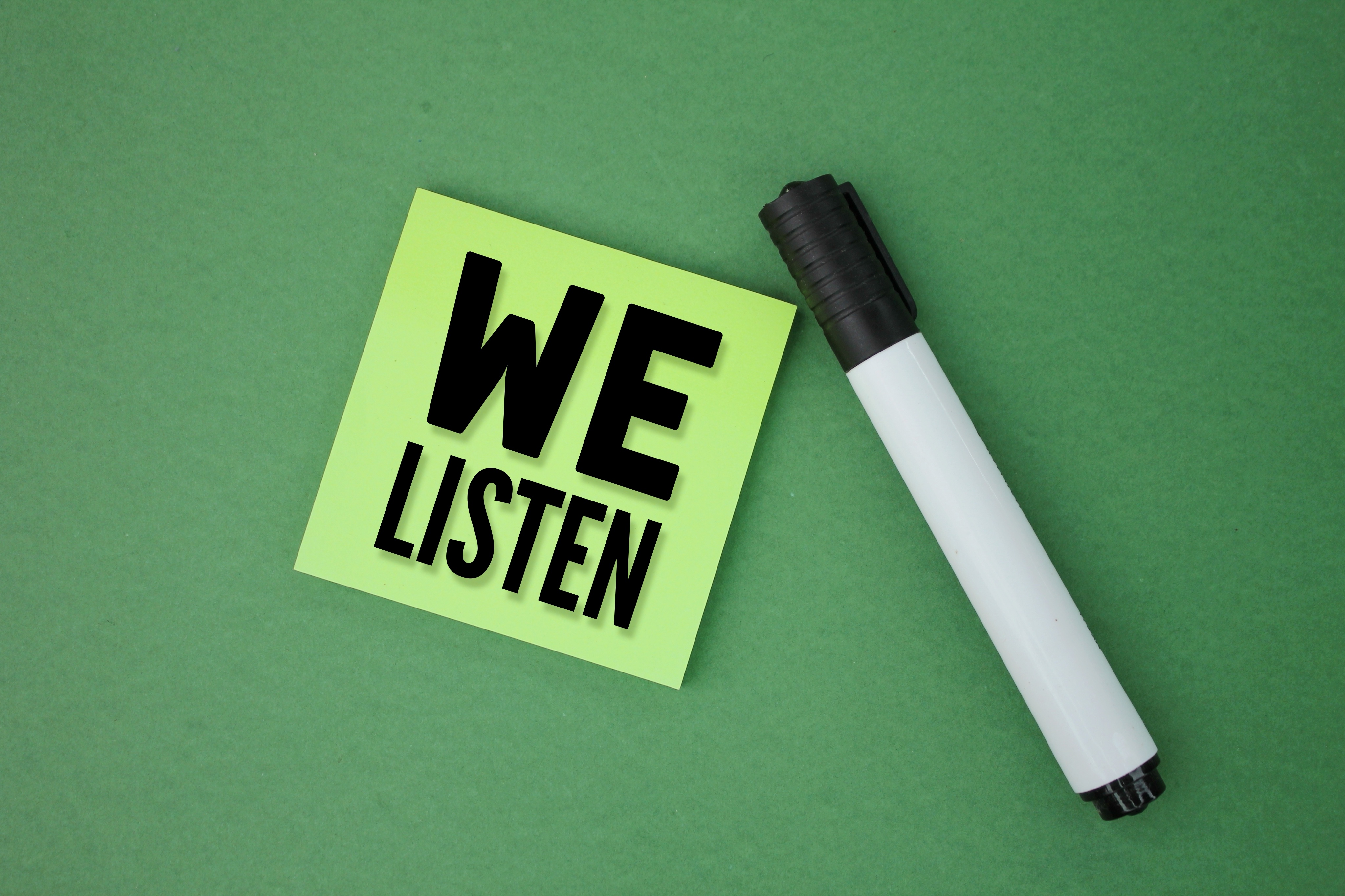 colored pen and paper with the word we listen. concept we hear. you speak we listen